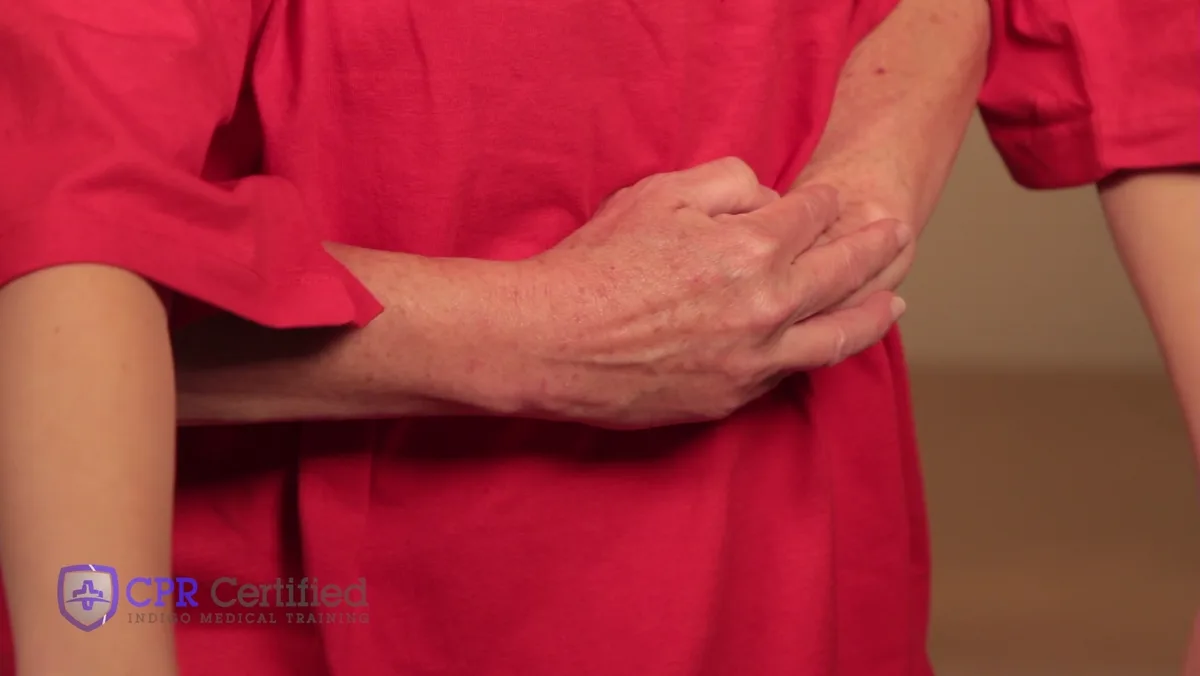 A rescuer's fist placed just above the navel with the other hand wrapped over it.