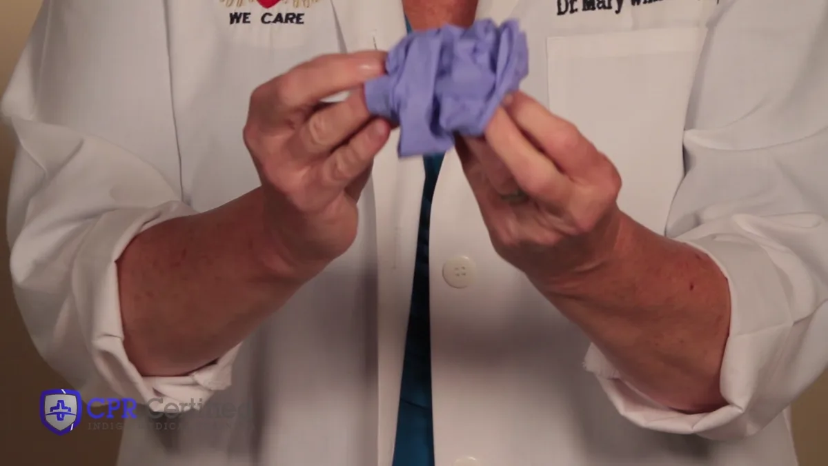 Both gloves balled together inside out in one bare hand, contaminated surfaces sealed inside.