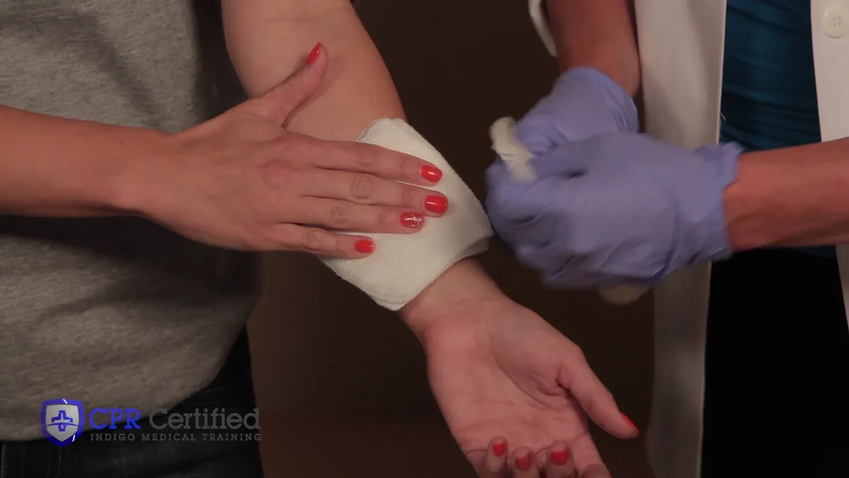 A rolled bandage being started at the wrist, at the end of the arm furthest from the body.
