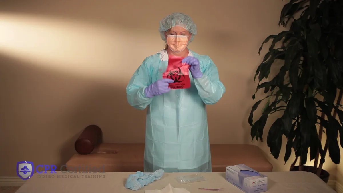 A worker in full protection holding up a red biohazard bag, ready for used equipment.